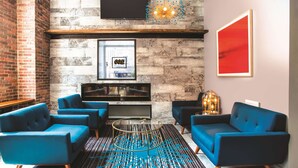 A modern living room with blue sofas, a coffee table, and a fireplace. - La Quinta Inn & Suites by Wyndham Baltimore Downtown (Baltimore)