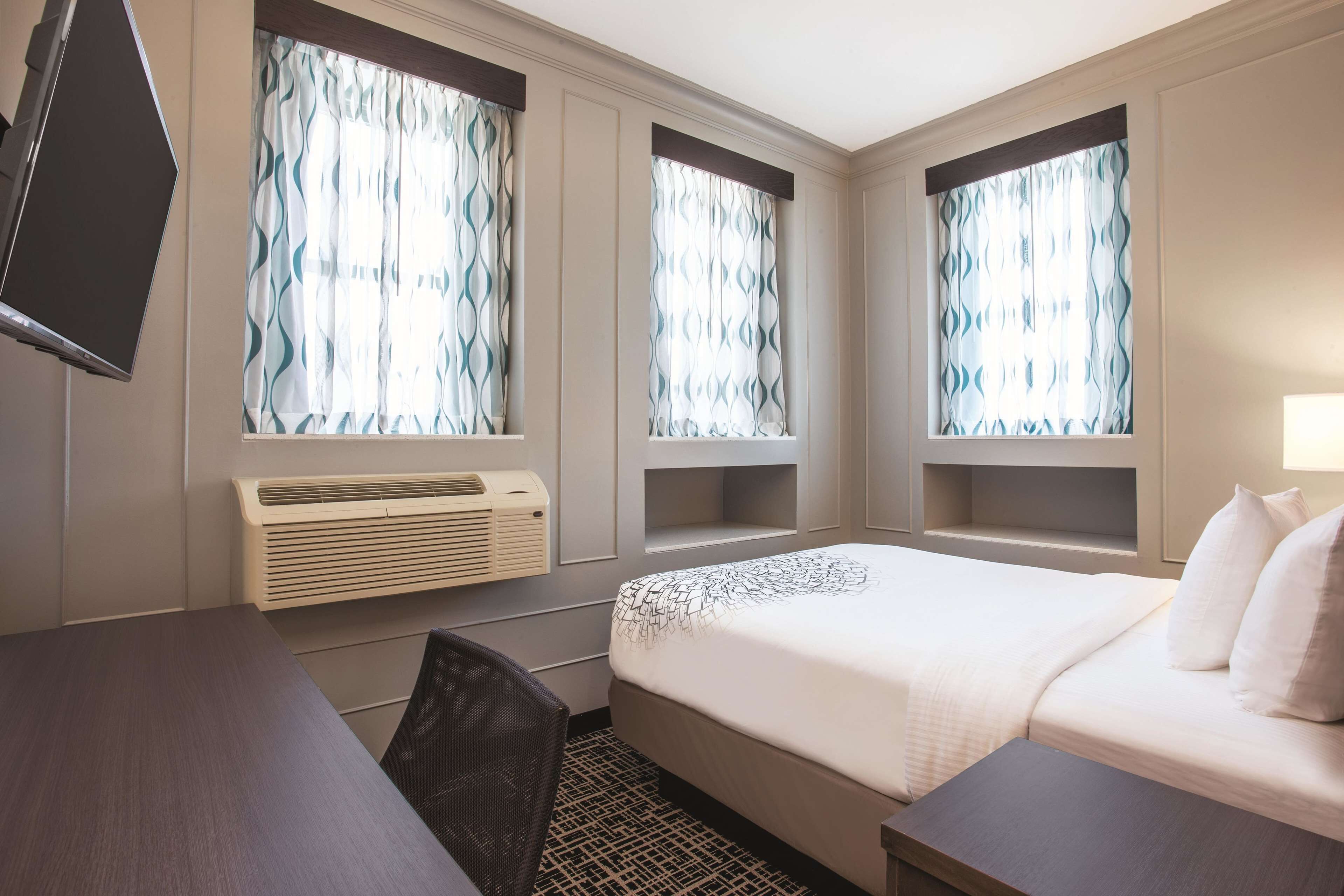 Una habitación de hotel con cama, escritorio, silla y televisor.