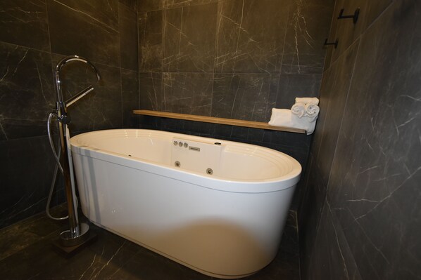 A modern bathroom with a freestanding bathtub, a handheld showerhead, and a towel rack. - Motel ANF (Drummondville)