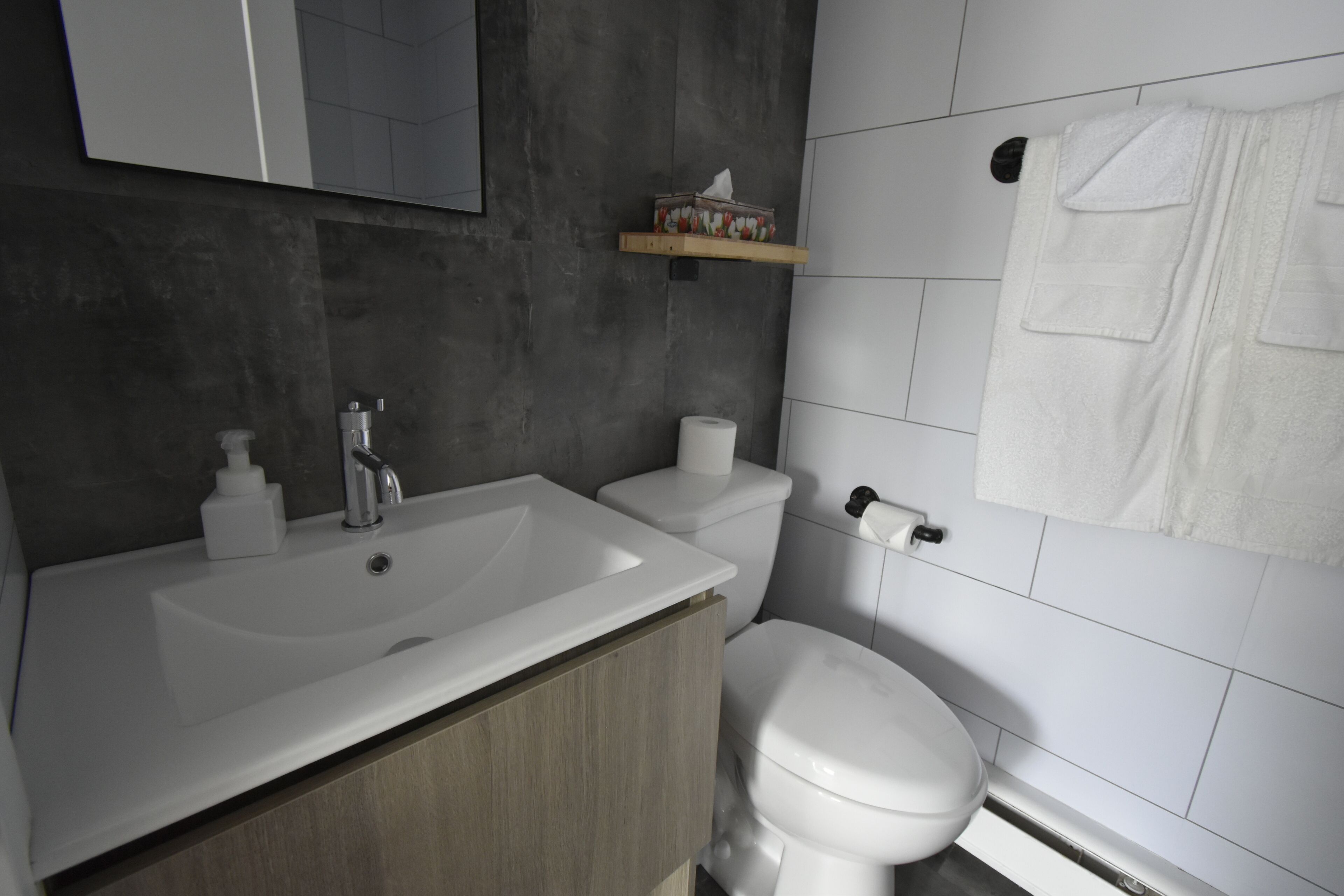A modern bathroom with a white sink, a toilet, and a towel hanging on the wall.