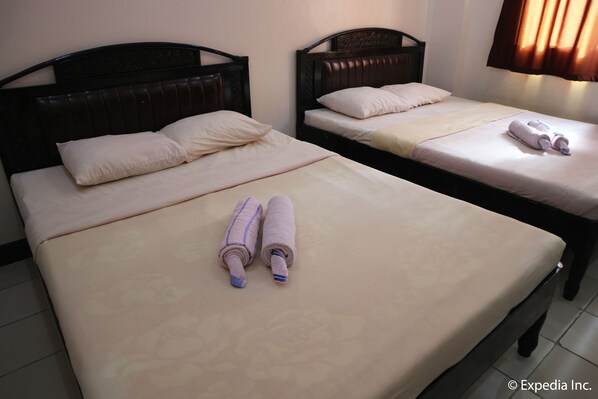 Two twin beds with headboards, a pair of rolled towels, and a window with curtains. - Boracay Travelodge Beach Resort (Boracay Island)