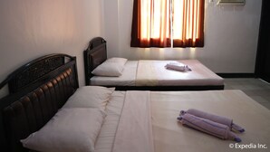 A room with two single beds, a headboard, a window with curtains, an air conditioning unit, and a tiled floor. - Boracay Travelodge Beach Resort (Boracay Island)