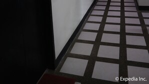 A hotel hallway with a checkered floor pattern, doors on both sides, and overhead lighting fixtures. - Boracay Travelodge Beach Resort (Boracay Island)