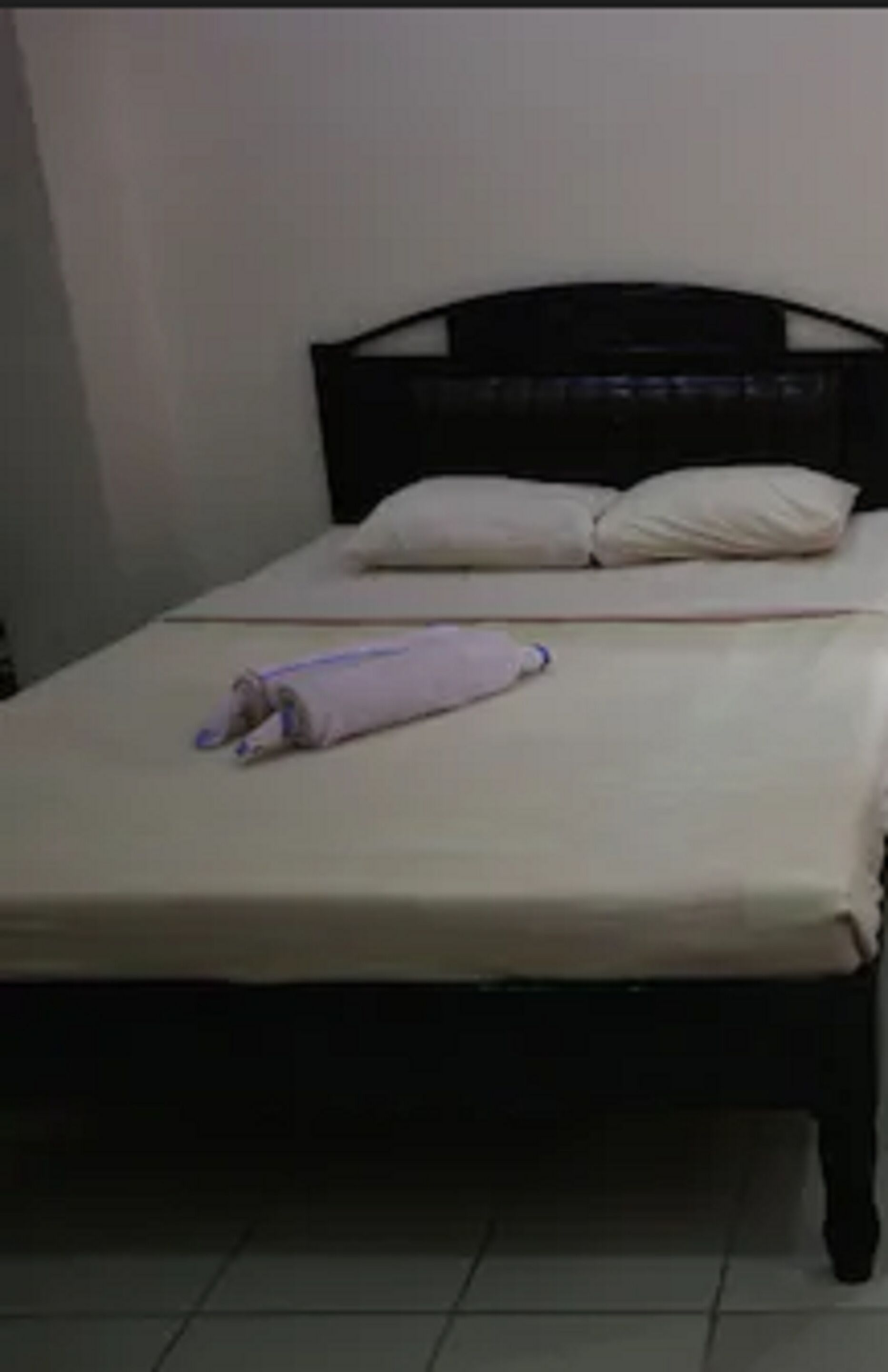 A bed with a white mattress and a folded blanket.
