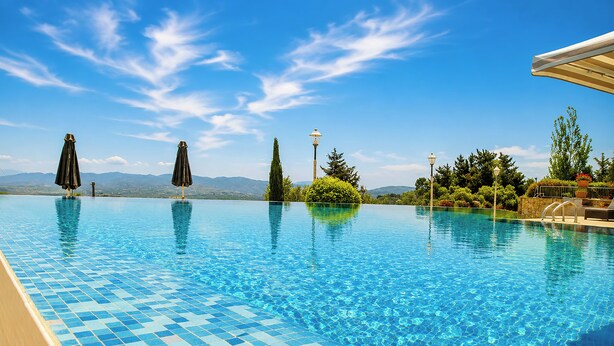 A clear blue swimming pool with tiled flooring, surrounded by greenery and a clear sky. - Droushia Heights (Droushia)