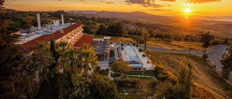 A hotel with a swimming pool, a parking area, and a view of the surrounding landscape.