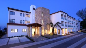 A modern hotel with a stone tower, multiple balconies, and a well-lit entrance. - Droushia Heights (Droushia)