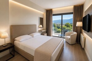 A hotel room with a bed, a chair, a TV, a window with a view, and a lamp. - Droushia Heights (Droushia)