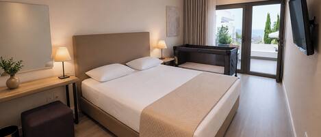 A hotel room with a bed, bedside tables, a TV, and a view of the outdoors.