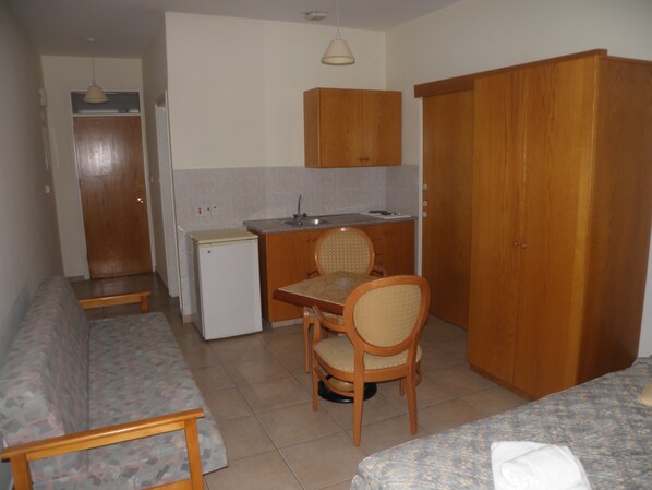 Una cocina compacta con comedor, un refrigerador pequeño, armarios de madera y una banca.