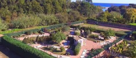 Un jardín ajardinado con senderos, un edificio pequeño y vistas al mar.