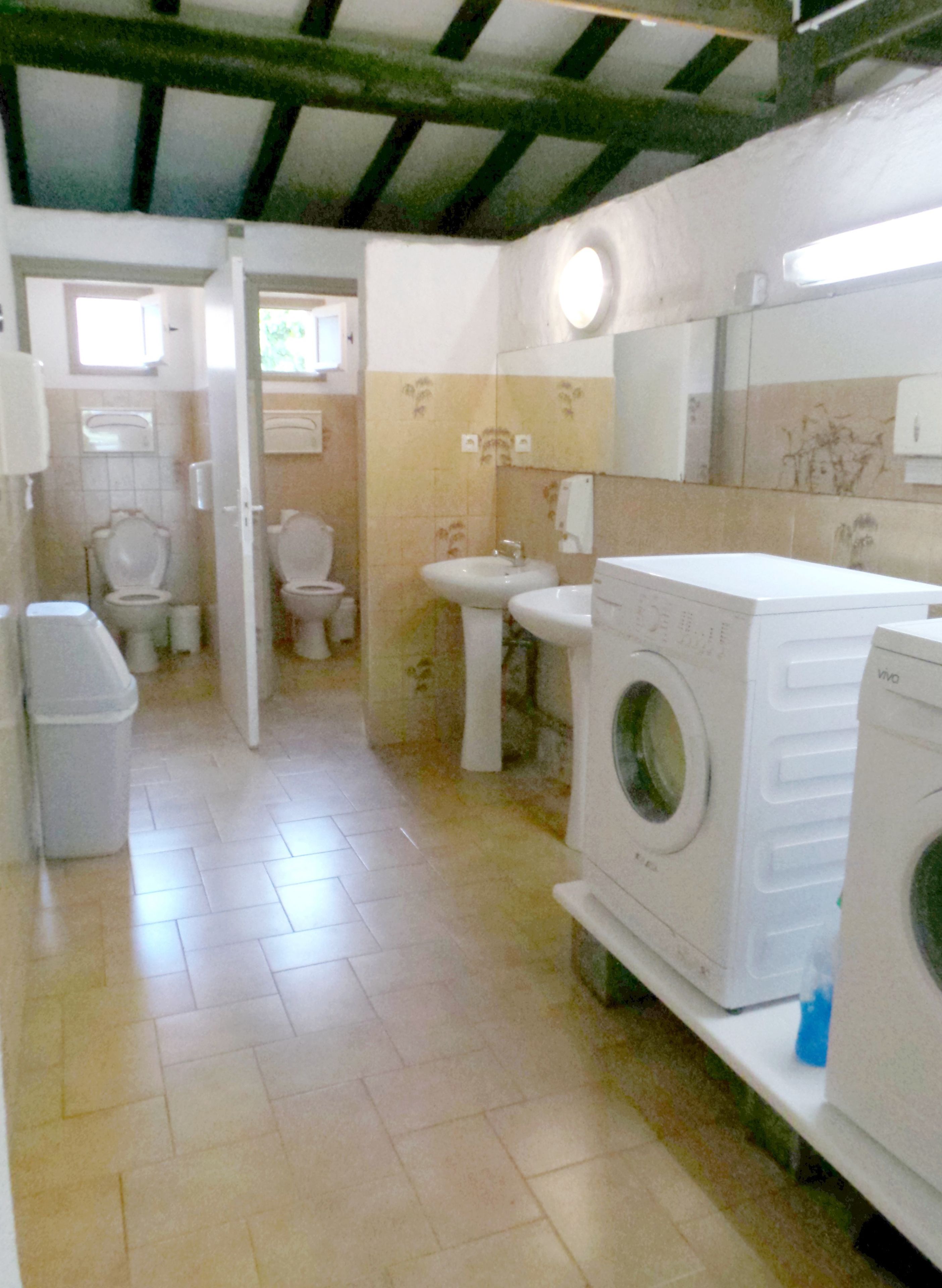 A small, clean bathroom with a toilet, sink, and washing machine.