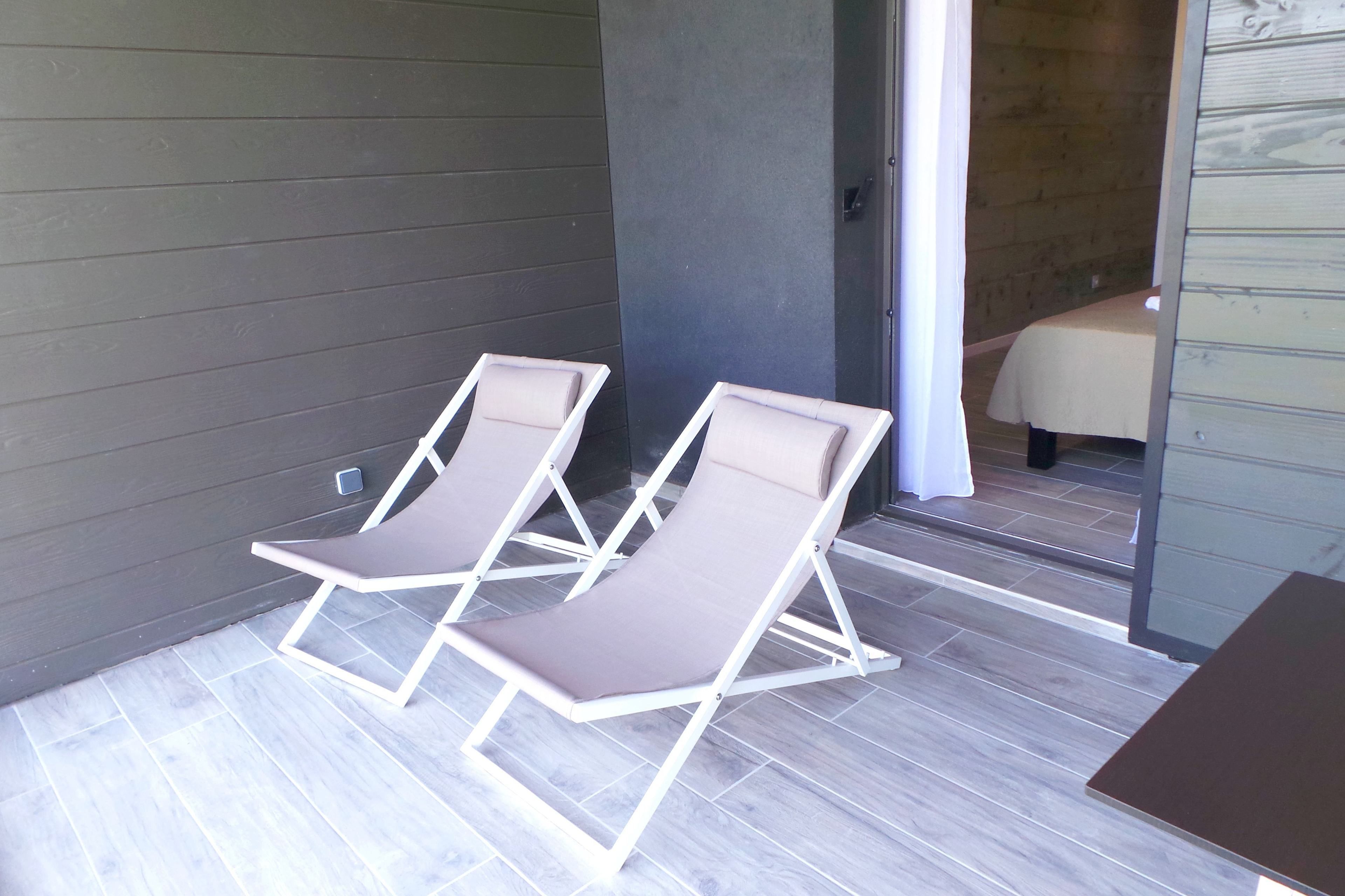 Two lounge chairs with a view of a wooden interior and a tiled floor.
