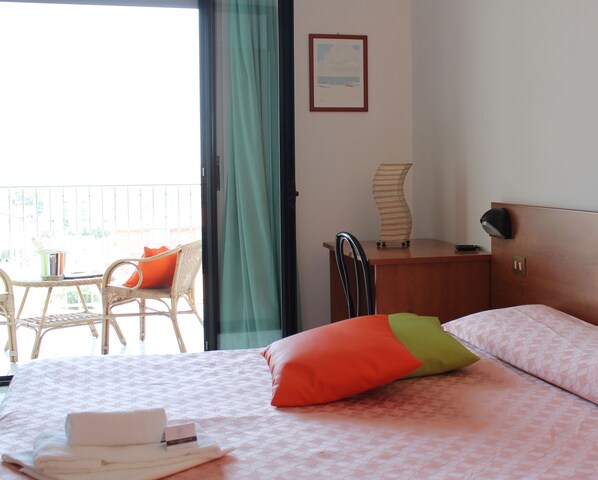 Habitación de hotel con cama, una silla, escritorio y vistas al exterior.