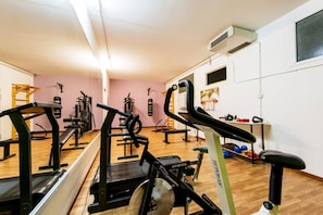 Une salle de sport équipée de divers appareils d’exercice, notamment des tapis de course, des vélos d’appartement et des appareils de musculation.