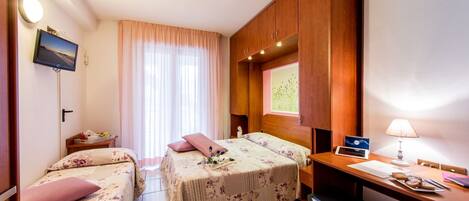 Une chambre d’hôtel avec deux lits, un bureau, une télévision et un réfrigérateur.