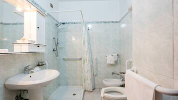 Un baño con ducha, dos lavamanos, inodoro y un perchero para toallas.