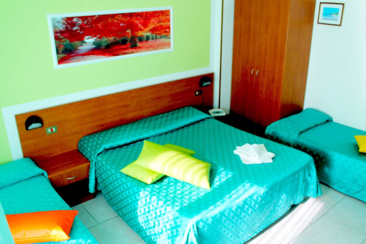 Un dormitorio con cama, dos mesitas de noche, un armario y un cuadro en la pared.
