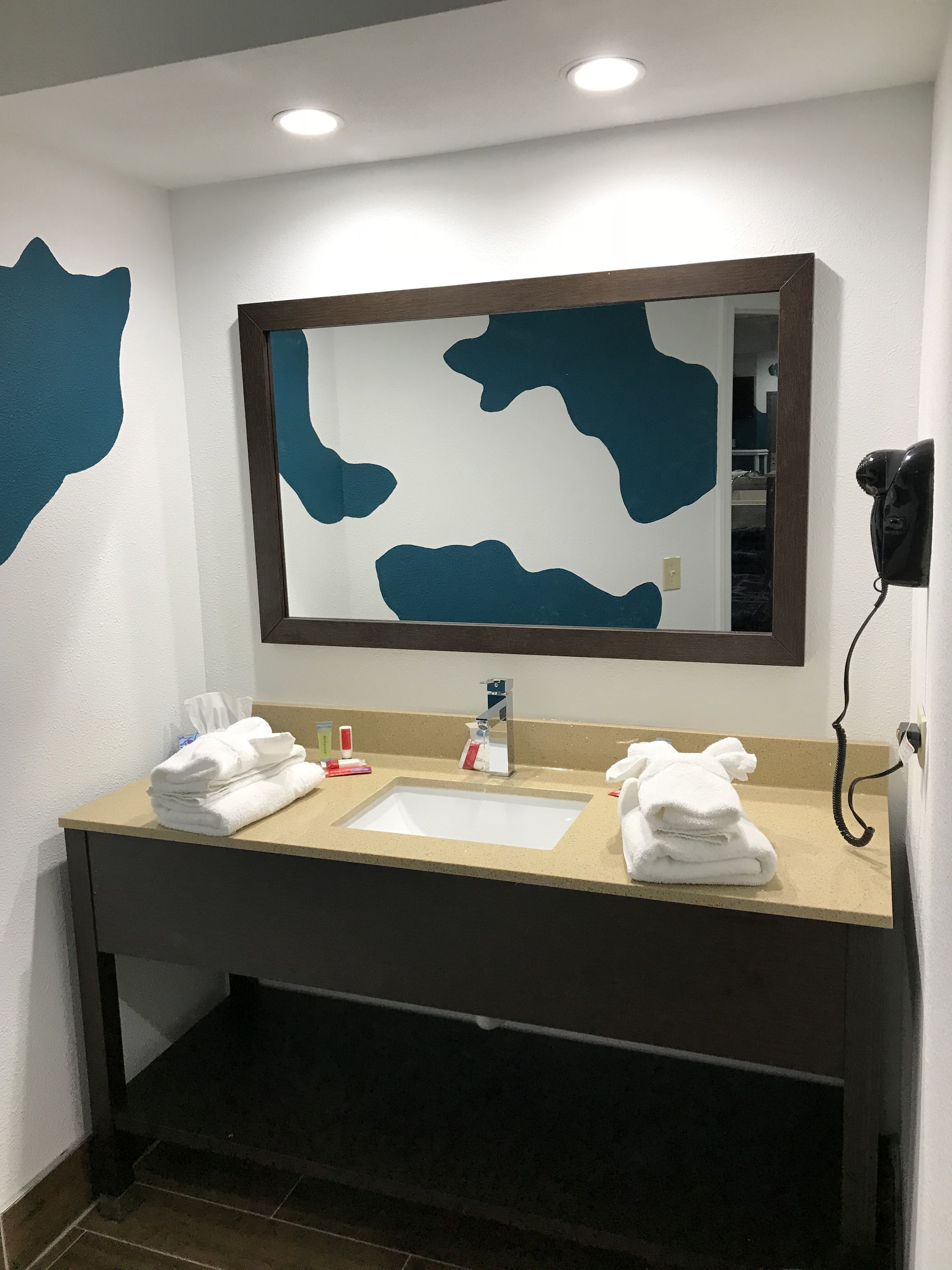 A hotel bathroom with a sink, mirror, and towels.