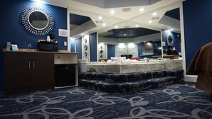 A hotel bathroom with a large mirror, a sink, and a patterned carpet. - Inn of the Dove (Cherry Hill)