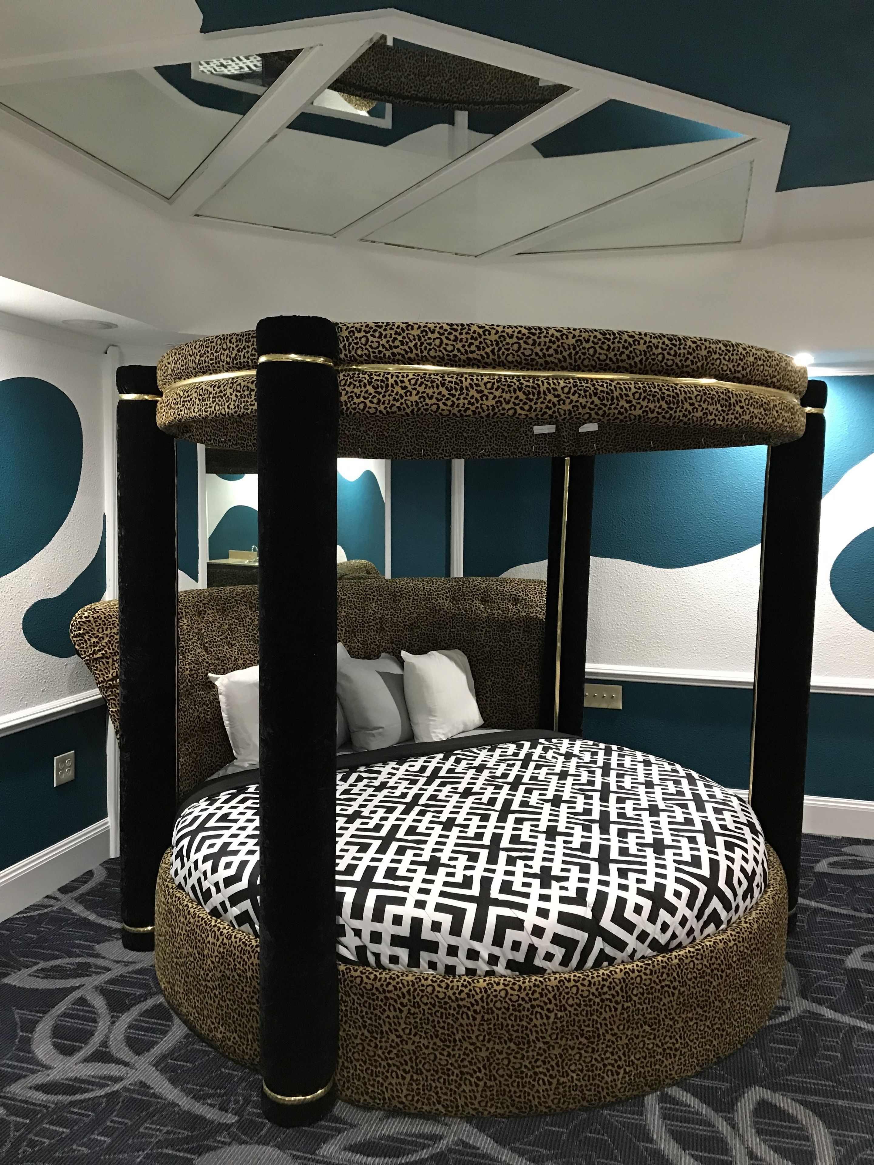 A four-poster bed with a leopard print canopy and a patterned bedspread.