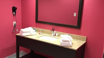 A bathroom with a double sink, a large mirror, and a hairdryer on the wall.