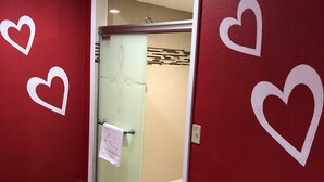 A hallway with red walls, a glass door leading to a bathroom, and wooden flooring. - Inn of the Dove (Cherry Hill)