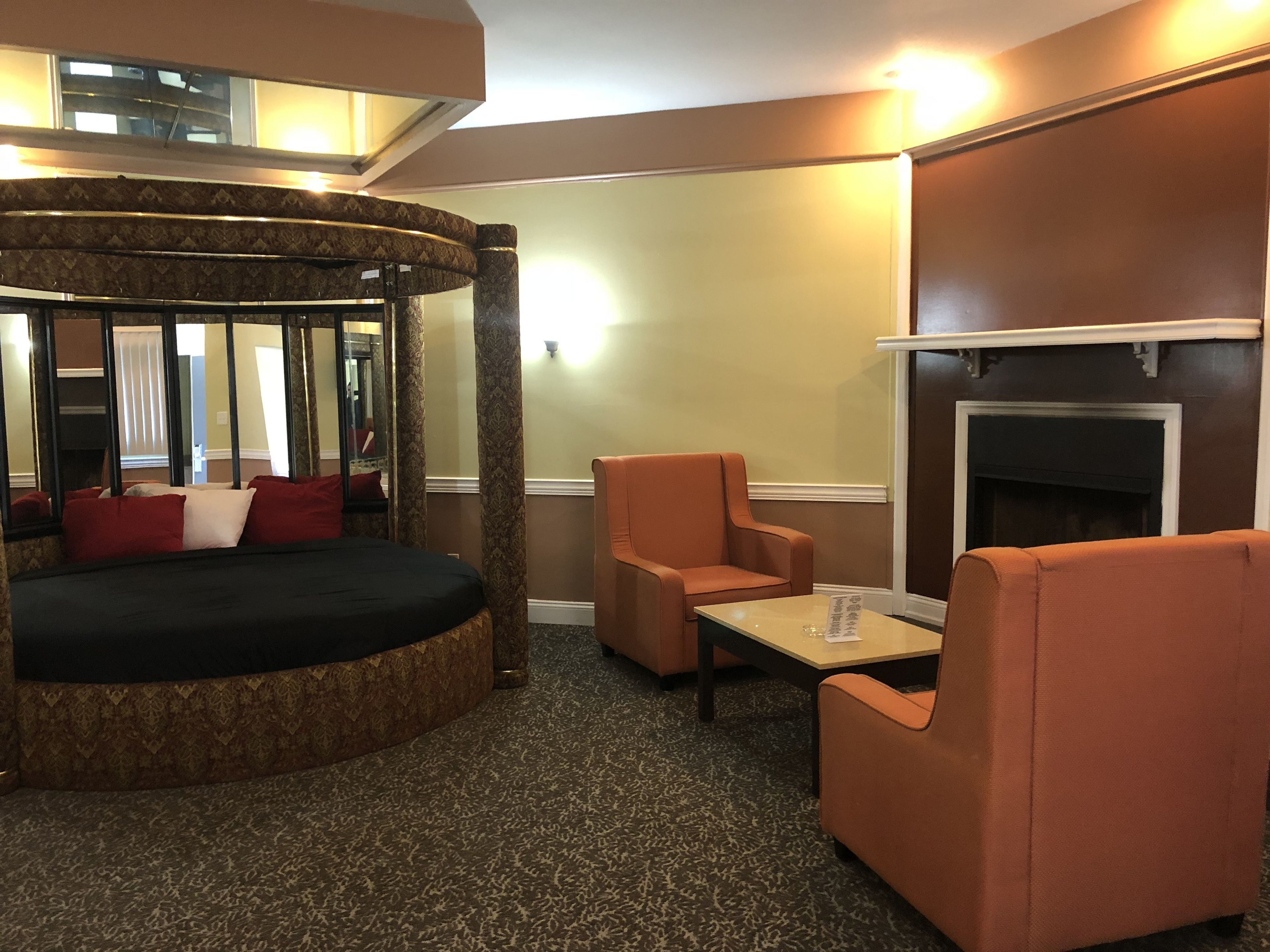A hotel room with a circular seating area, a fireplace, and two armchairs.