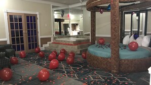 A hotel room with a large bed, a sitting area with a chair, a bathroom with a bathtub, and a staircase leading to an upper floor. - Inn of the Dove (Cherry Hill)