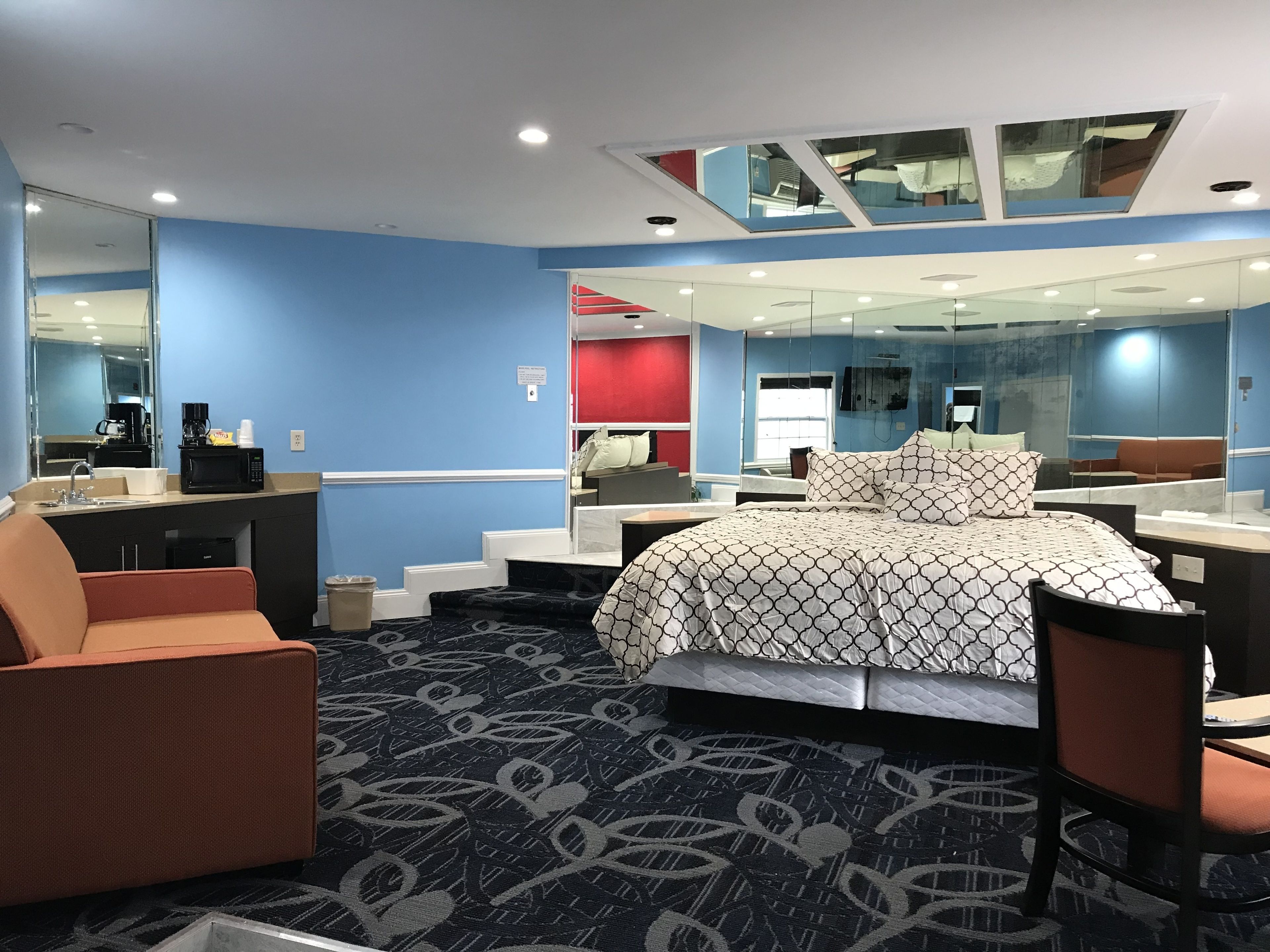 Une chambre d’hôtel équipée d’un lit, d’un bureau, d’une chaise, d’un canapé, d’un miroir et d’une kitchenette.