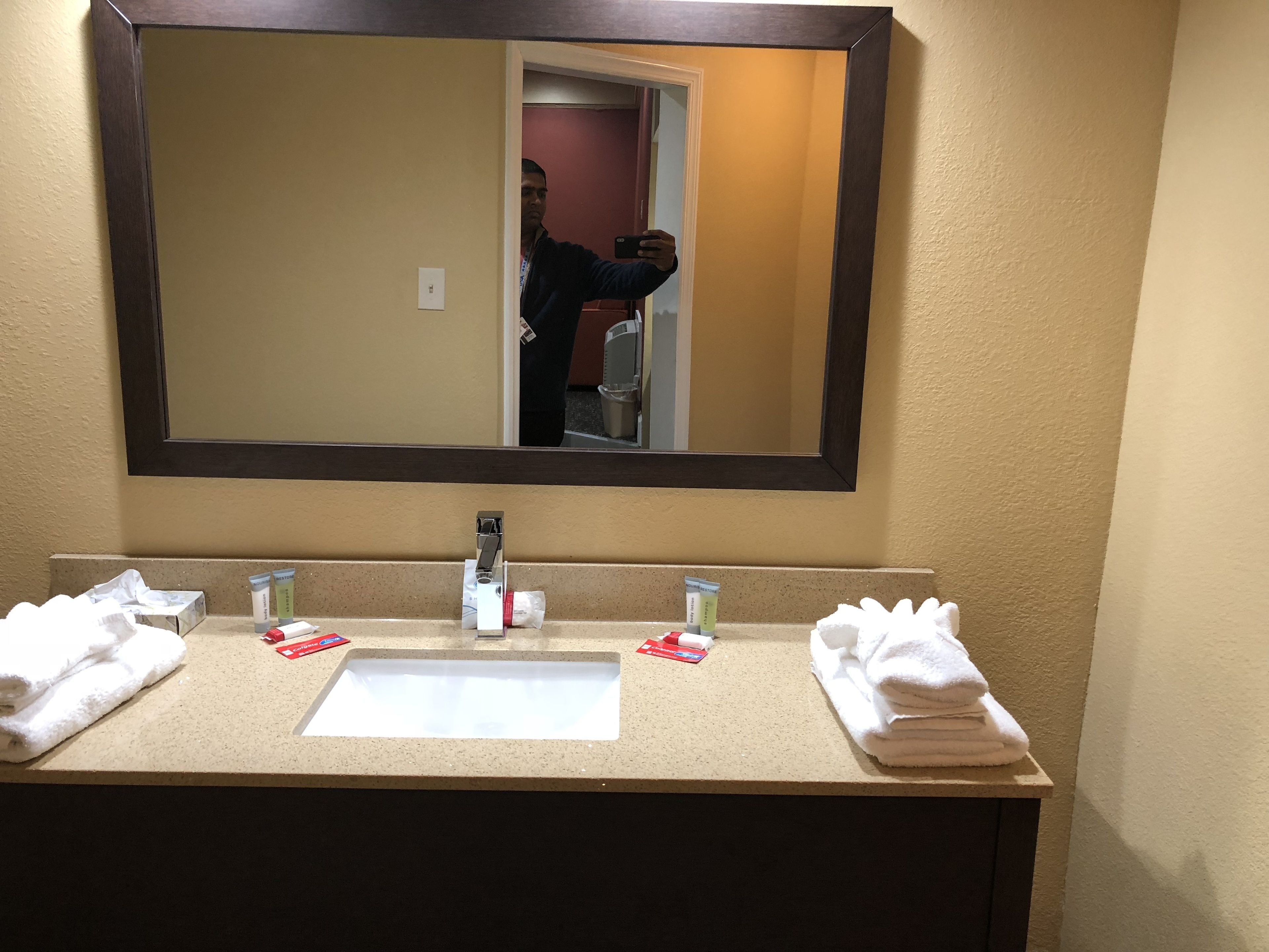 A hotel bathroom with a large mirror, a sink, and two towels.