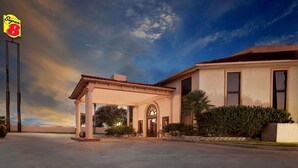 A hotel with a covered entrance, large windows, and a well-maintained lawn.
