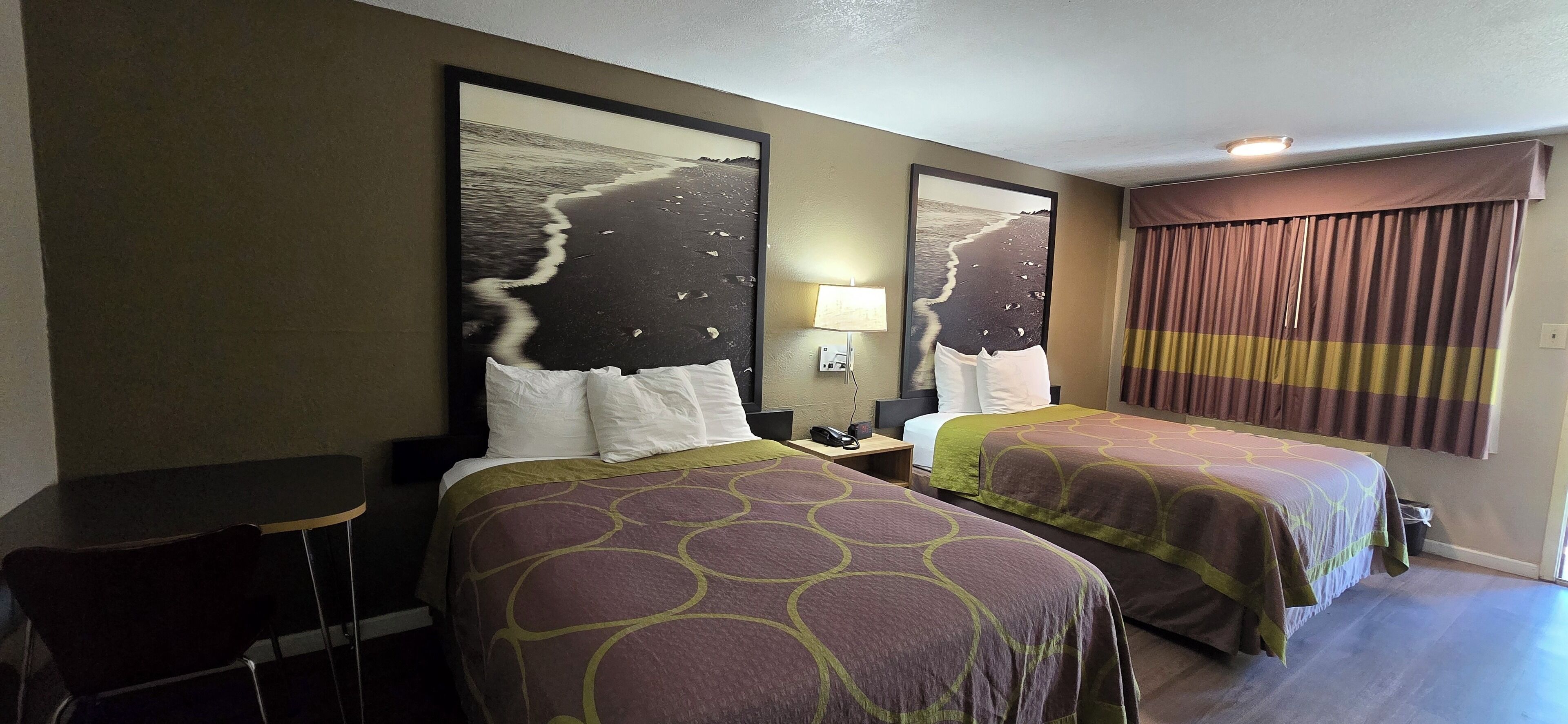 A hotel room with two beds, a desk, and a chair.