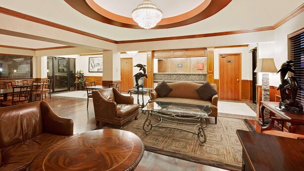 A spacious lobby with leather sofas, a coffee table, and a chandelier.
