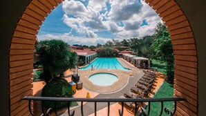Vista de una piscina con sillas de descanso y un pequeño puente, enmarcado por un arco de ladrillo.