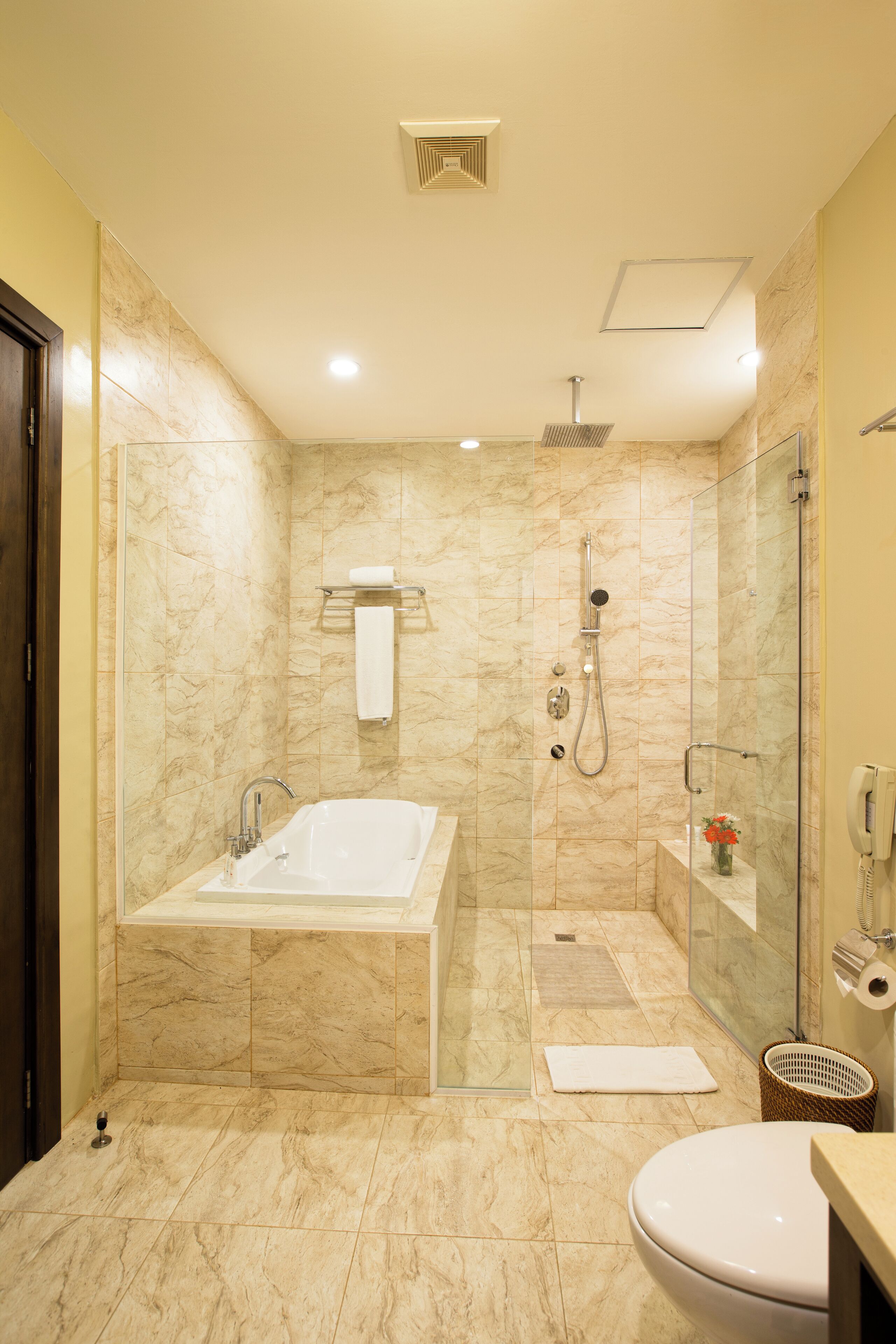 A modern bathroom with a glass-enclosed shower, a freestanding bathtub, and a toilet.