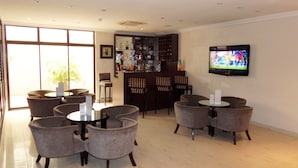 A hotel lobby with a bar area, multiple seating arrangements, and a television on the wall. - S&S Hotels and Suites (Lagos)