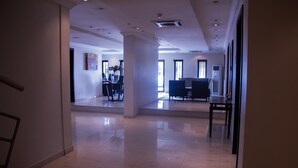 A spacious, well-lit hallway with a modern design, leading to a dining area with a large table and chairs. - S&S Hotels and Suites (Lagos)
