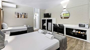 Une chambre d’hôtel avec un grand lit, un bureau avec une chaise, une télévision, un four à micro-ondes et une petite kitchenette.