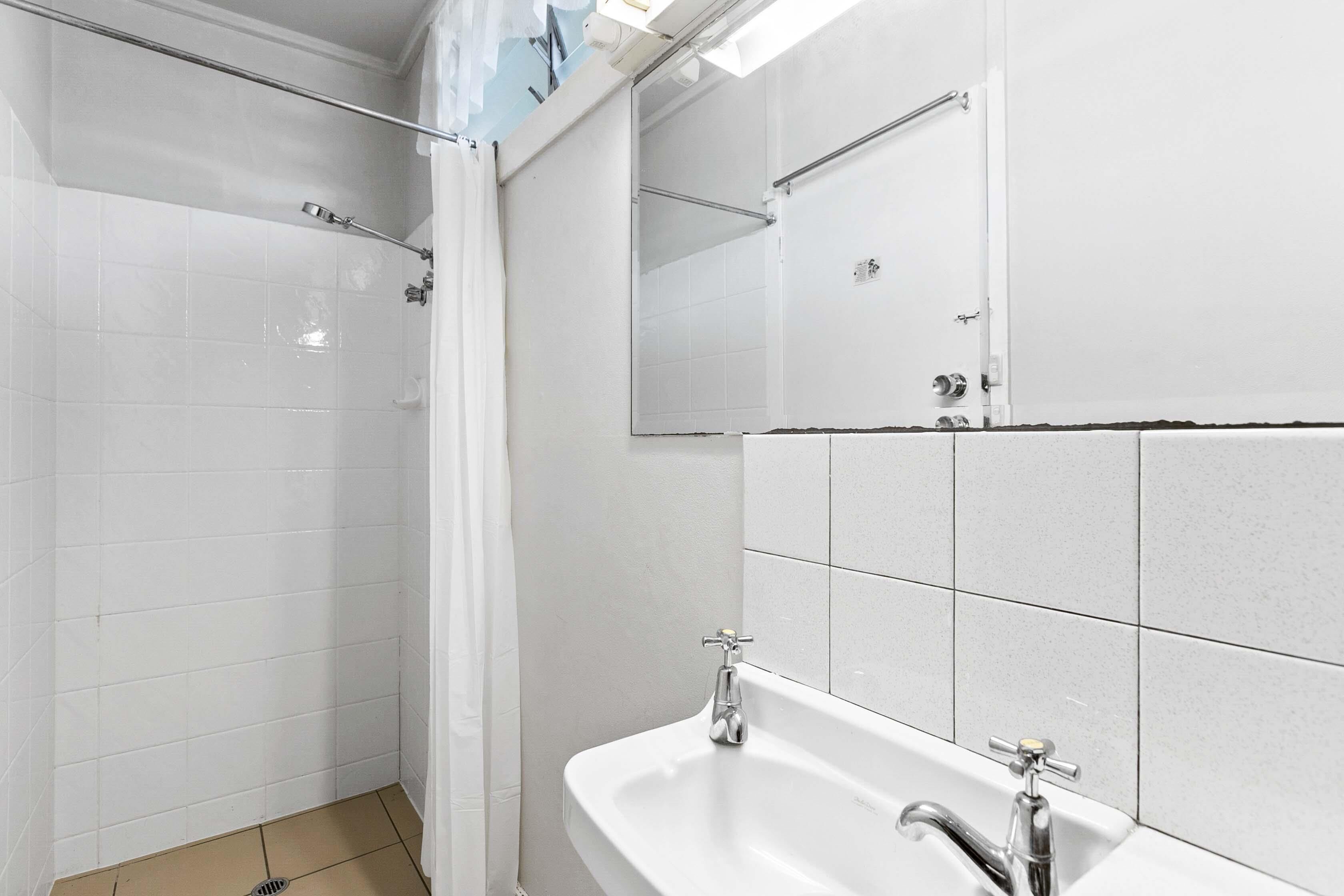 A bathroom with a shower, a sink, and a mirror.