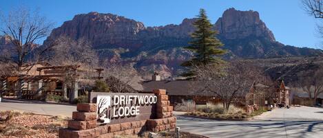 A sign for Driftwood Lodge with a mountainous backdrop.