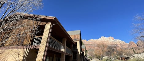A building with a brick facade, a balcony, and a view of red rock formations.
