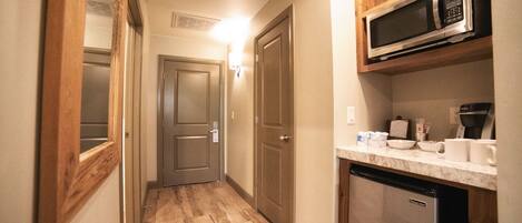 A narrow hallway with wooden flooring, a microwave on a shelf, and a dishwasher.
