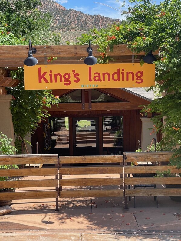 Un banco de madera frente a un edificio con un letrero que dice 'king's landing bistro'.