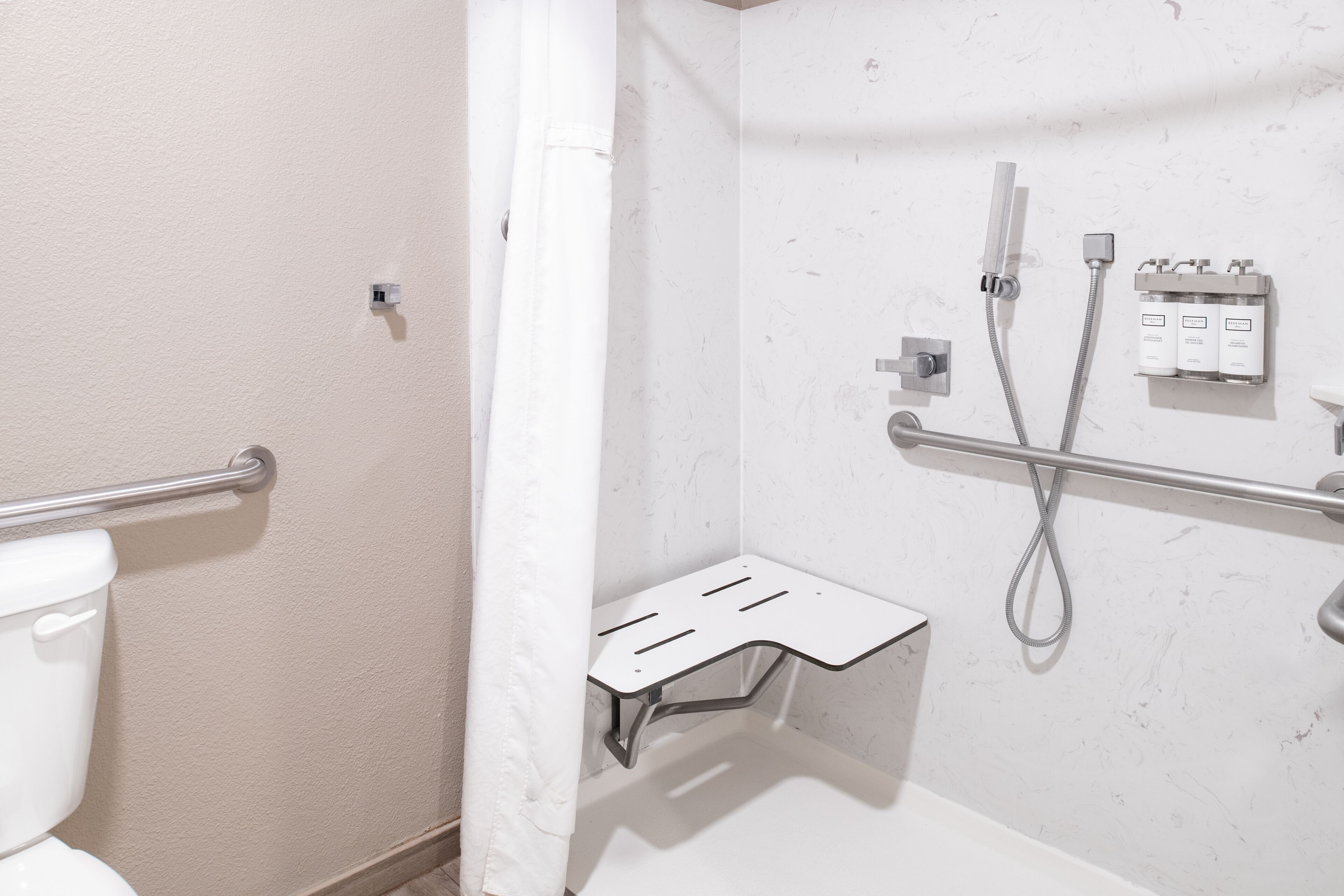 A bathroom with a shower, toilet, and a towel rack.