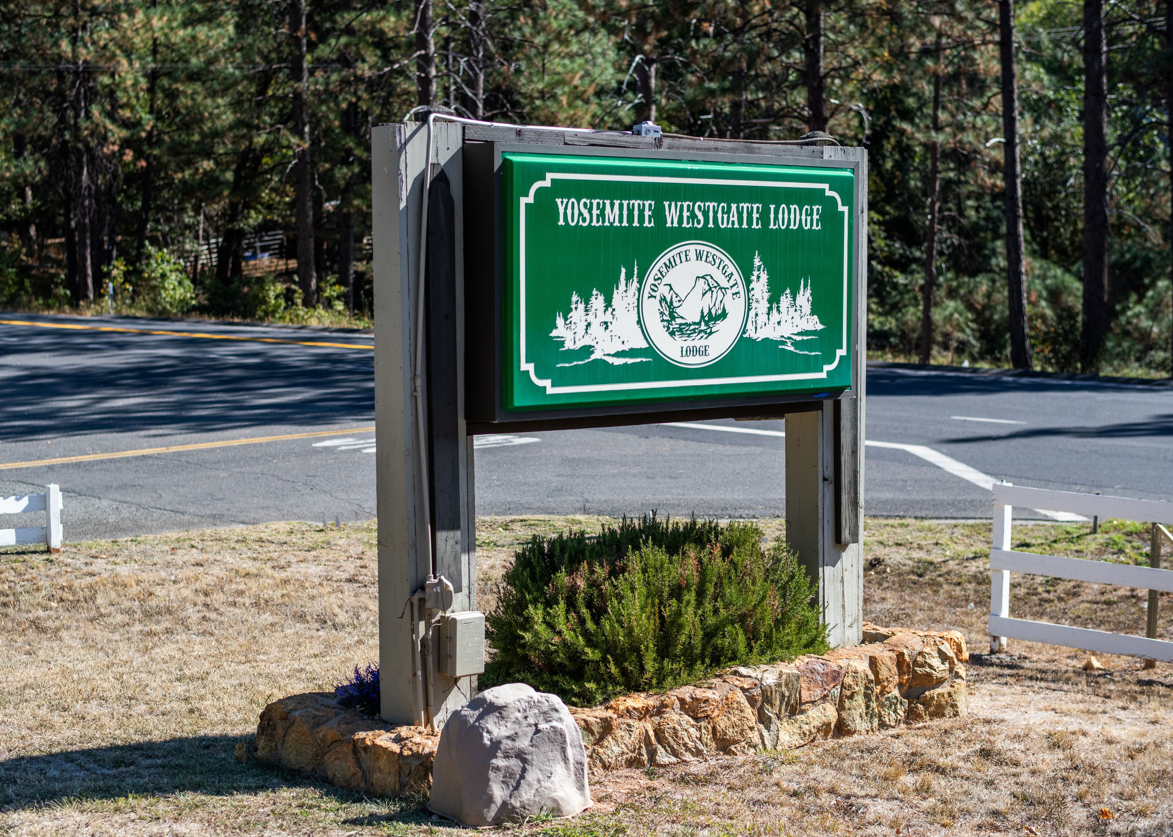 A sign for Yosemite Westgate Lodge with a mountainous landscape illustration.