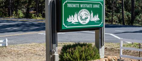 A sign for Yosemite Westgate Lodge with a mountainous landscape illustration.