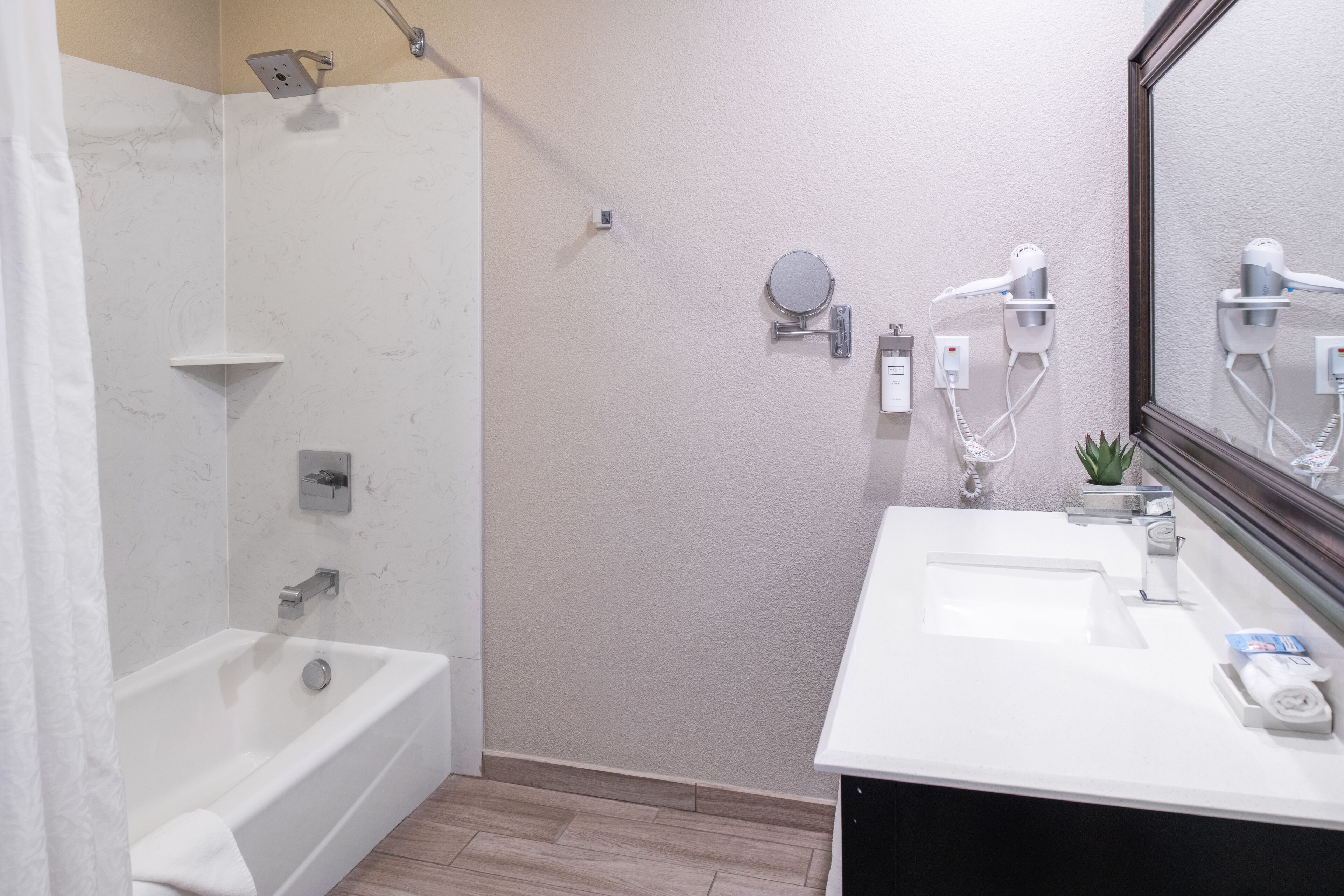 A modern bathroom with a bathtub, a shower, and a vanity with a mirror.