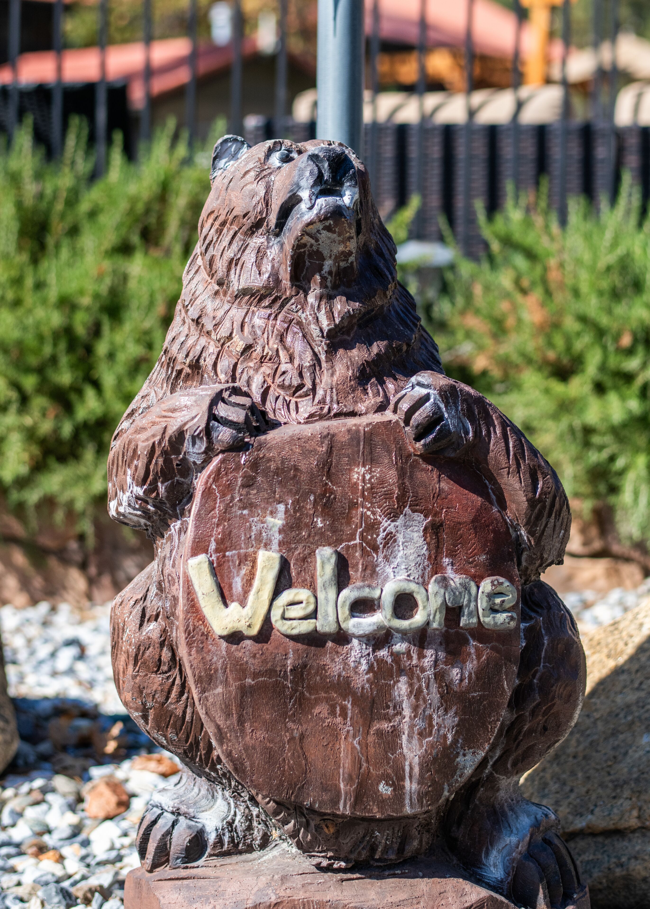 Escultura de madera de un oso con la palabra 'Welcome' en un cartel.
