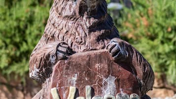 Escultura de madera de un oso con la palabra 'Welcome' en un cartel.